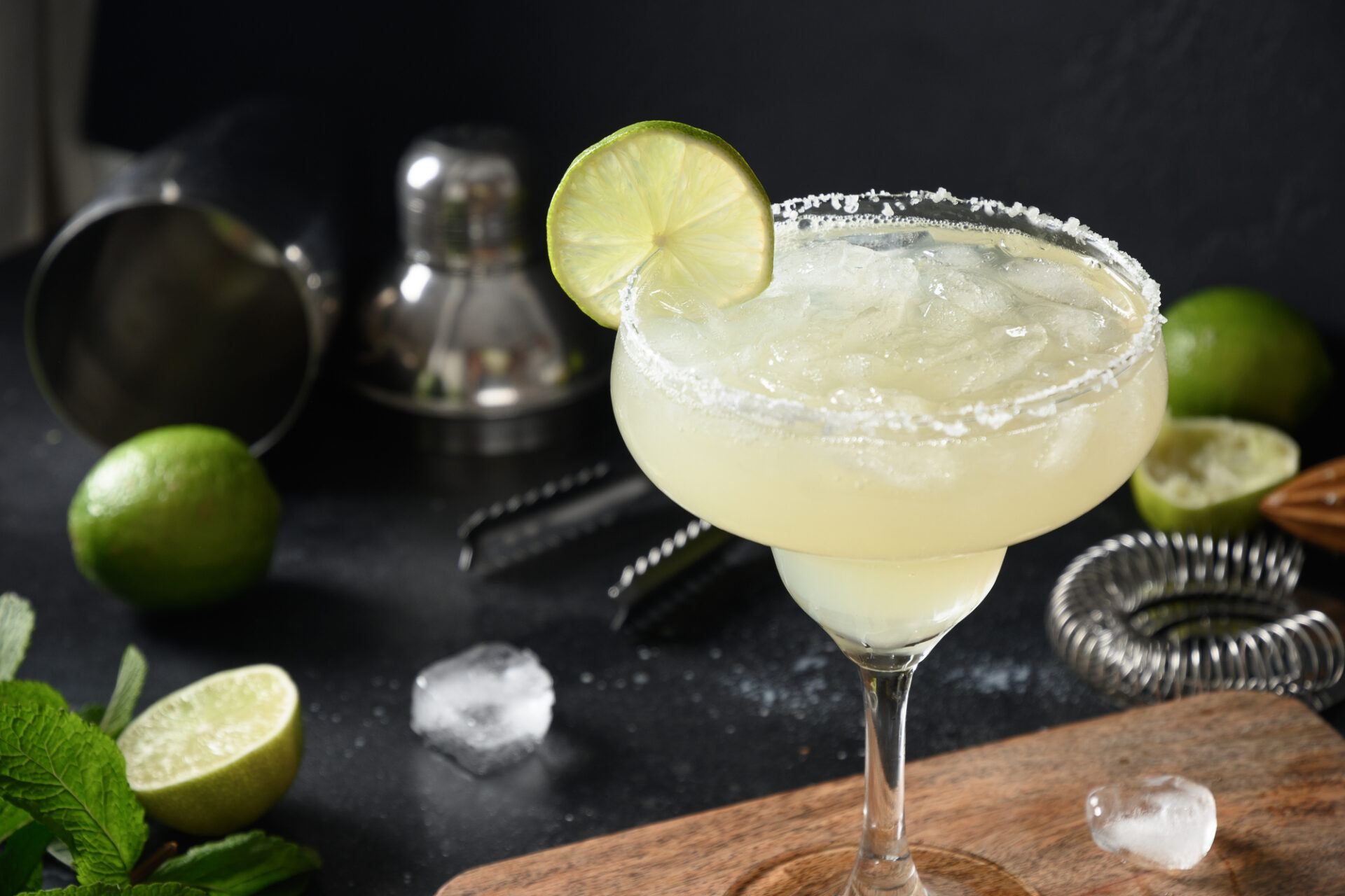 Margarita cocktail garnish lime and ice cube on black background.